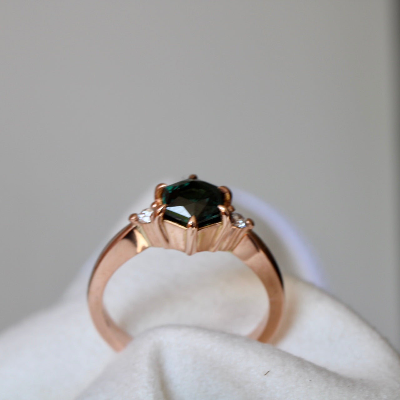 Vibrant Australian Green hexagonal Cut Sapphire & Diamond Helena ring. The sapphire is set with six eagle claws. The stone is beautifully complimented by two 2mm 0.03pt Round Brilliant cut diamonds total diamond weight 0.06pts and is set in 14ct Rose gold. The Sapphire measures 6.8mm & is 1.45cts The ring is size O (can be sized J-R) Made with recycled metal in Sydney Ethically sourced Gemstones