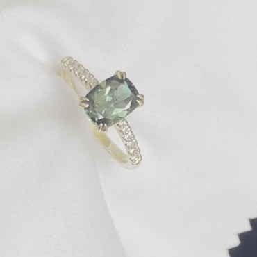 A Teal Green Australian Parti Sapphire from Rubyvale in QLD & is set with four double claws. The stone is beautifully complimented by 12 x Round Brilliant cut graduating diamonds total diamond weight 0.13pts and is set in 14ct Yellow gold.  The Sapphire measures 7.9 x 5.9mm & is 1.75ct   Available in Size M  Made with recycled metal in Sydney   Ethically sourced Gemstones 