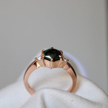 Vibrant Australian Green hexagonal Cut Sapphire & Diamond Helena ring. The sapphire is set with six eagle claws. The stone is beautifully complimented by two 2mm 0.03pt Round Brilliant cut diamonds total diamond weight 0.06pts and is set in 14ct Rose gold.  The Sapphire measures 6.8mm & is 1.45cts   The ring is size O (can be sized J-R)   Made with recycled metal in Sydney   Ethically sourced Gemstones 
