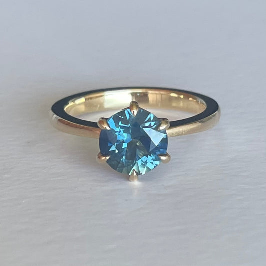 This 14ct Yellow Gold Solitare Chloe Sapphire Ring featuring a Light Blue Australian Parti Sapphire and is set with 6 claws. The band is pinched at the top, the claws are set in an eagle claw shape   The Sapphire measures 7.5mm & is 1.69ct in weight  This ring is a size L (it can be resized I-Q)   Made with recycled metal in Sydney   Ethically sourced Gemstones 
