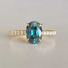 Load image into Gallery viewer, Oval Teal Sapphire ring set in four claws. The stone is beautifully complimented and by twelve 1.7mm round brilliant cut Diamonds and is set in 18ct yellow gold.  The Sapphire is 9 x 6.5mm 2.47ct, total diamond weight is approximately 0.24pts  The ring is Size L   Made with recycled metal in Sydney   Ethically sourced Gemstones 